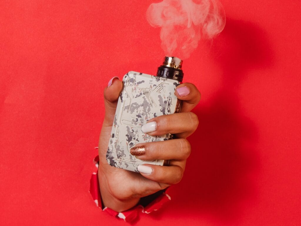 girl hand ataching working vape machine red background